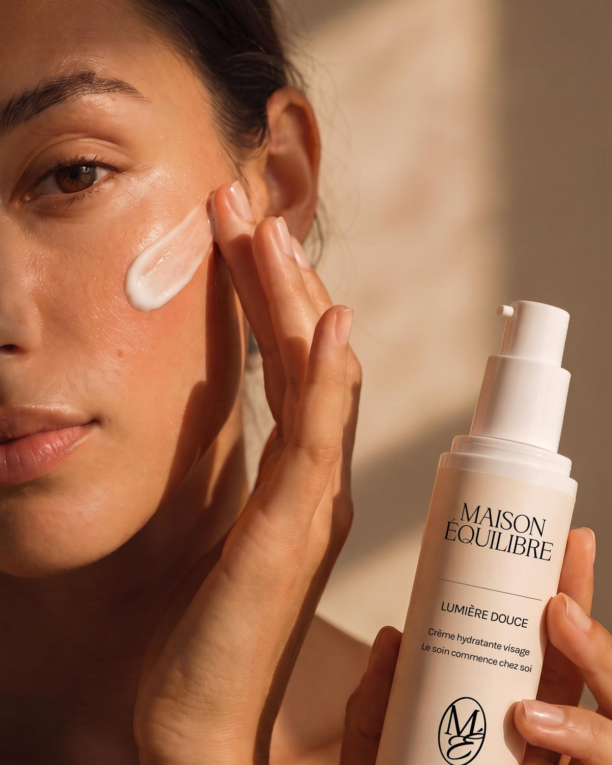 Femme appliquant la crème hydratante Lumière Douce sur sa joue.