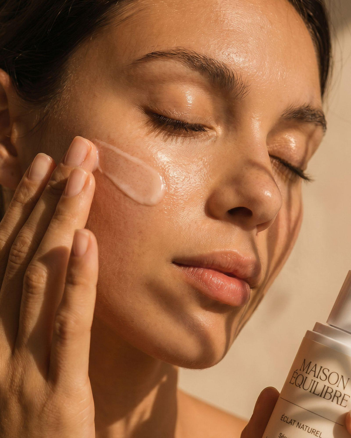 Femme appliquant le sérum Éclat Naturel sur sa joue.