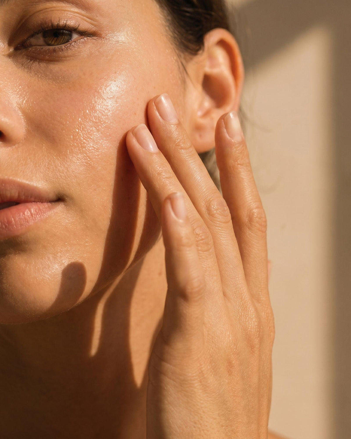 Femme faisant pénétrer un soin du visage sur sa joue.