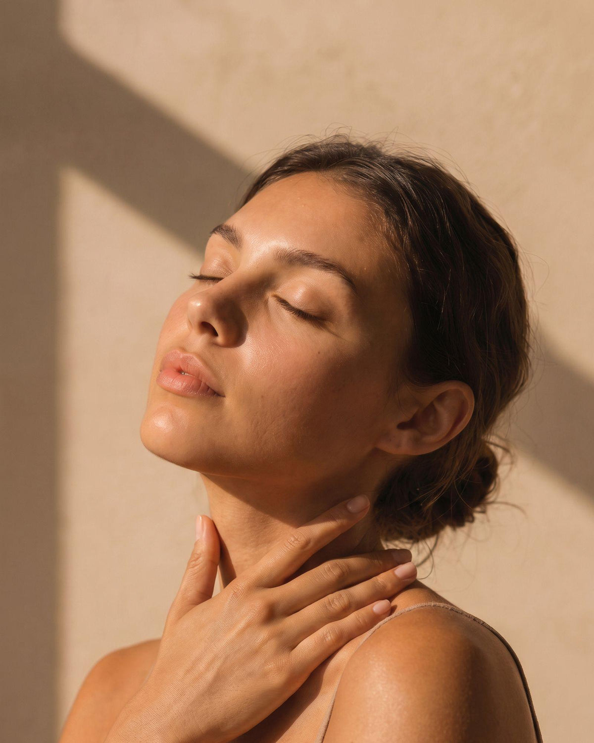 Femme posant ses mains sur son cou pendant un rituel de bien-être.