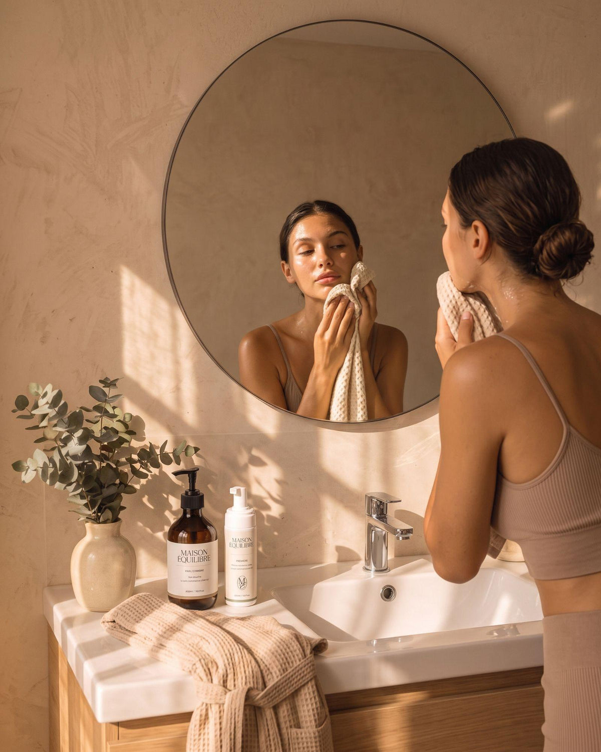 Femme réalisant sa routine de soins Maison Équilibre devant son miroir.
