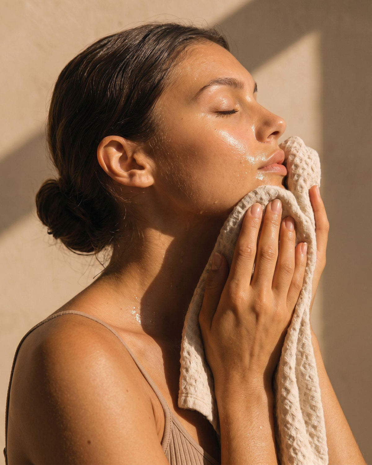 Femme séchant délicatement son visage après le nettoyage avec Première.