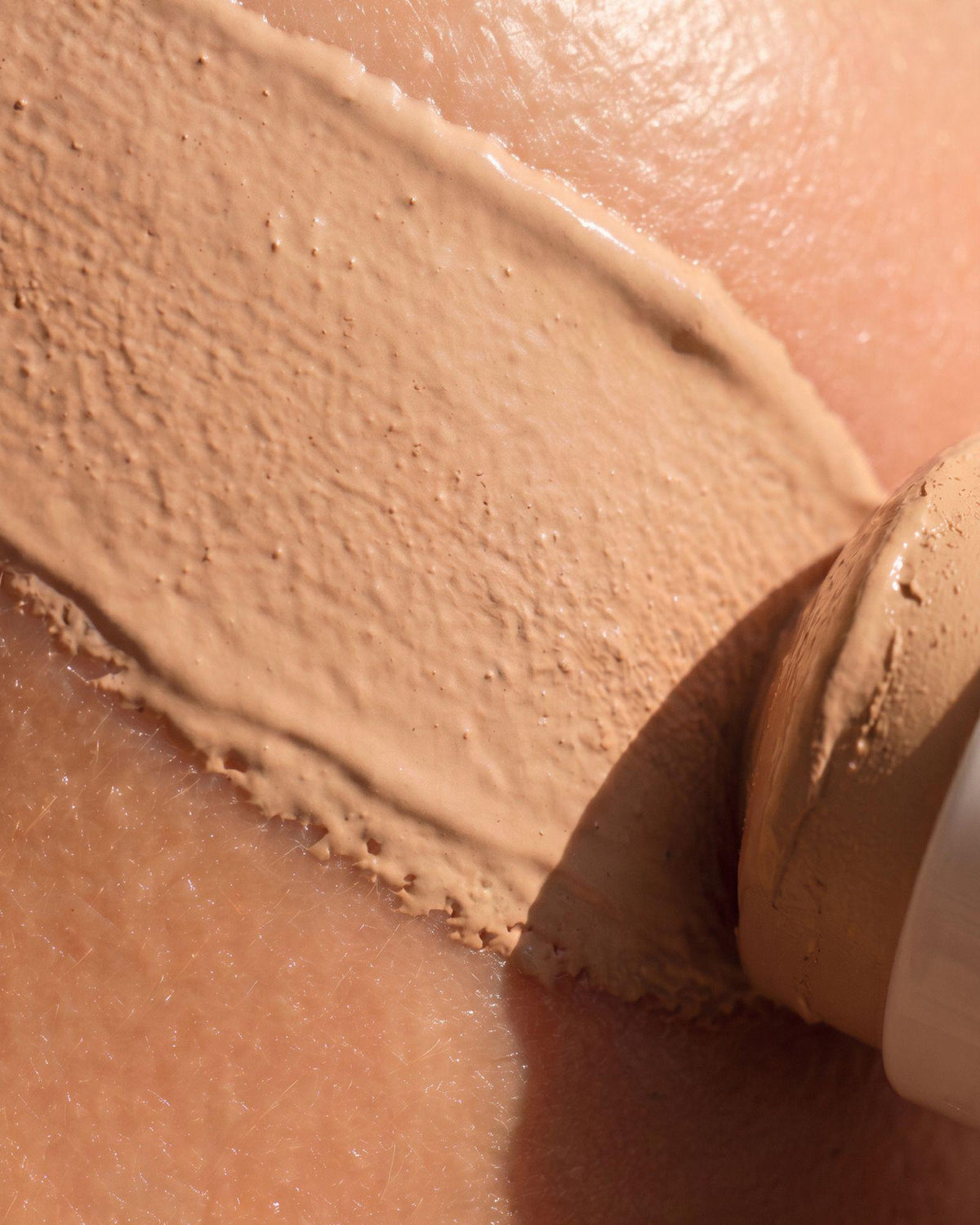 Gros plan sur le passage du stick solaire SPF 50 Voile Protecteur sur la peau.